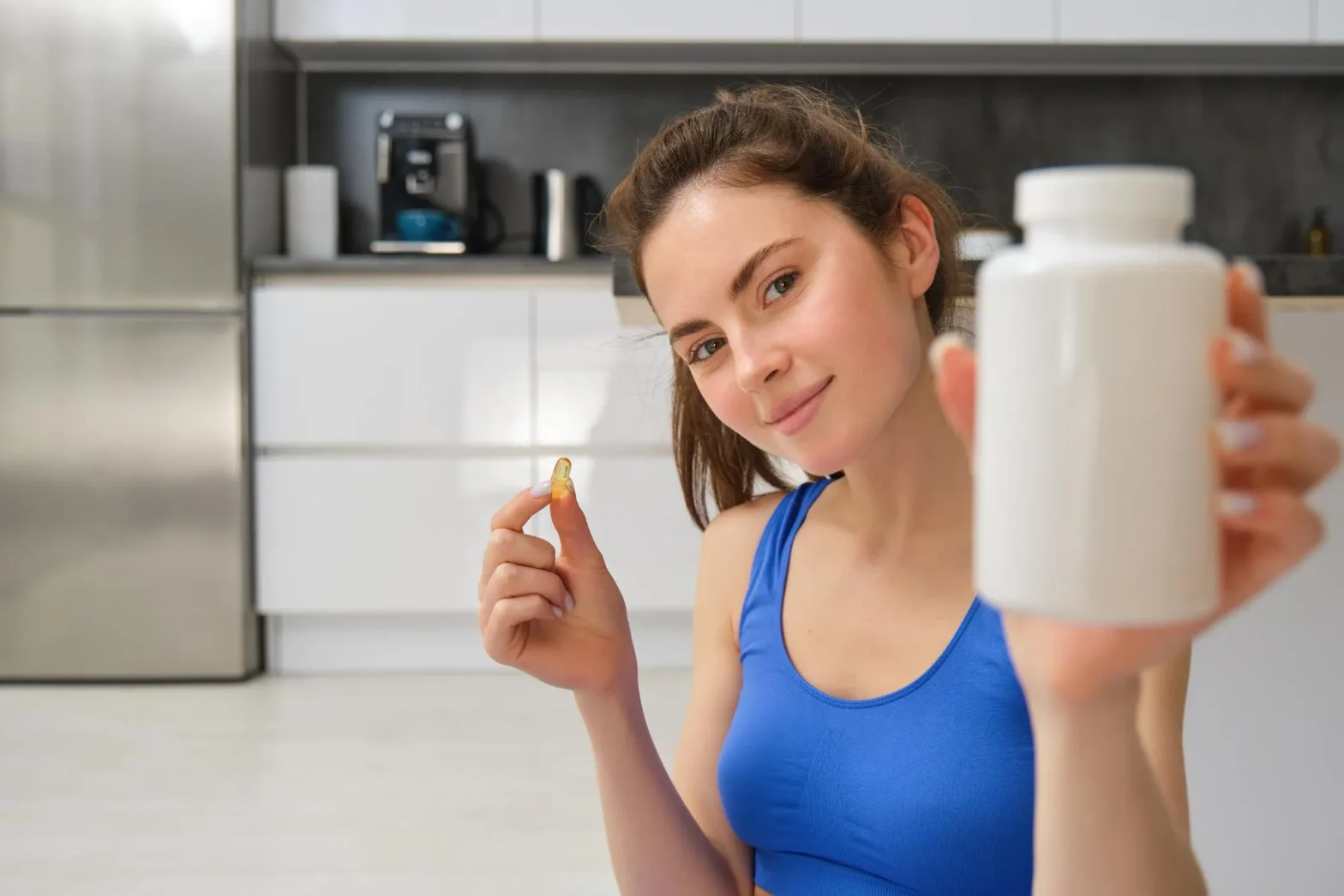 A woman holding a supplement capsule and bottle, highlighting the importance of choosing suitable vitamins and supplements to support individual wellness needs.