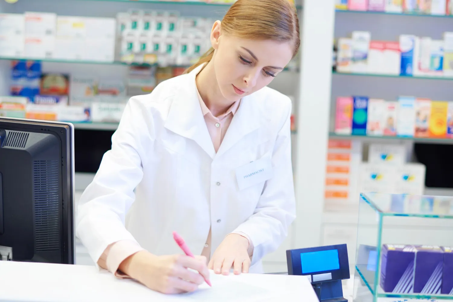 Pharmacist reviewing prescription information while preparing medication in a pharmacy, highlighting the role of Pharmacists.
