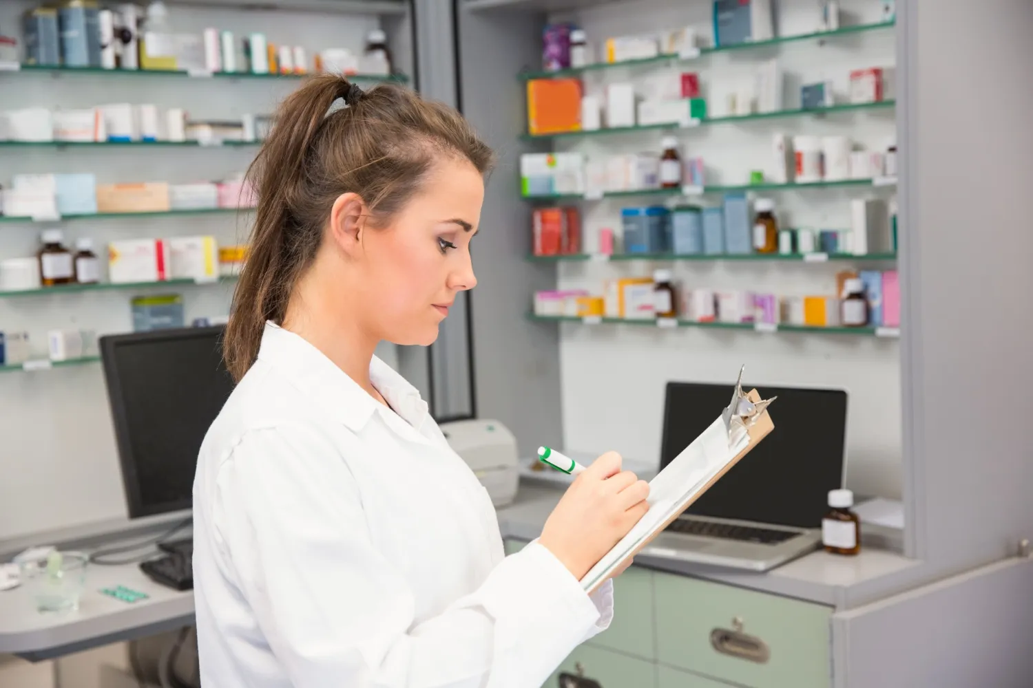Pharmacist checking medication inventory and prescriptions in a pharmacy.
