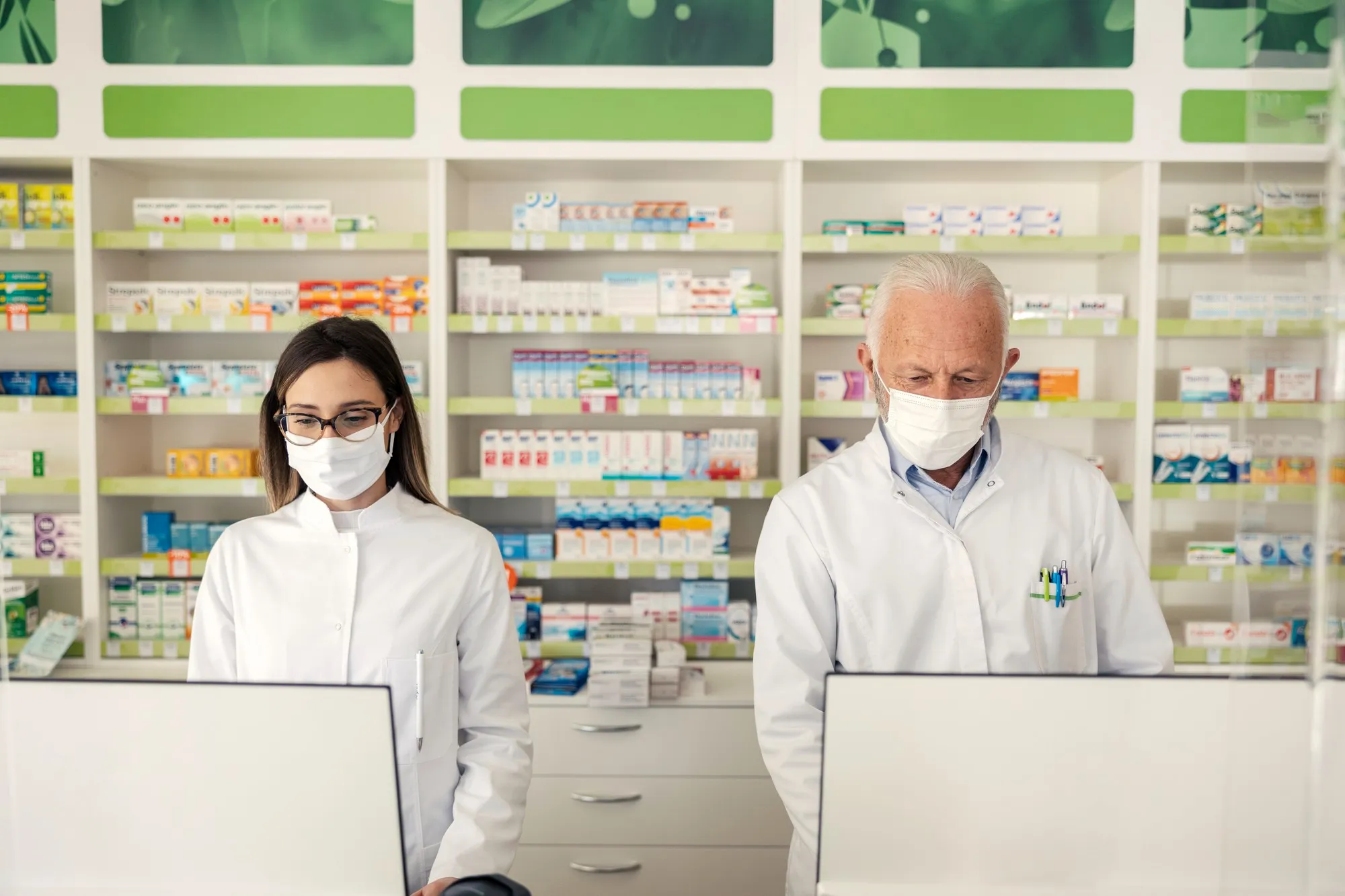 Pharmacists working on computers inside a pharmacy, representing specialty pharmacy services focused on managing complex medications, ensuring accuracy, and supporting patient care