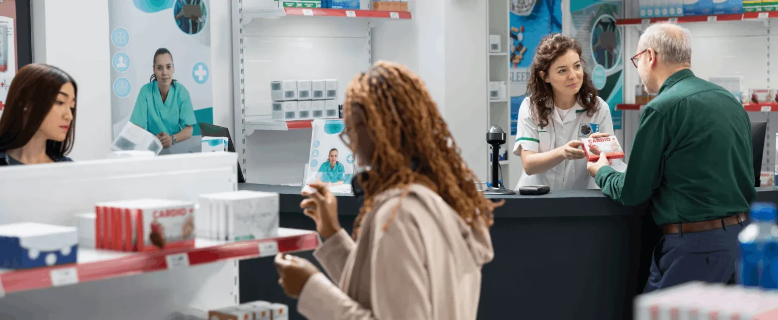 Pharmacy setting where a pharmacist assists a customer, representing accessible pharmacy clinical services and personalized medication guidance in a clinical community pharmacy