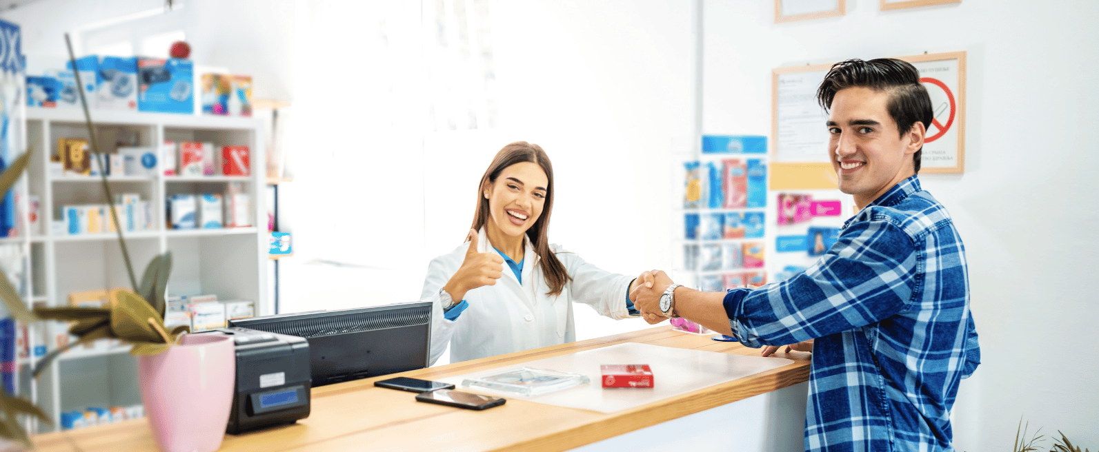Pharmacist smiling and giving a thumbs-up while assisting a customer at the pharmacy counter, representing professional Pharmacy Clinical Services and patient support.