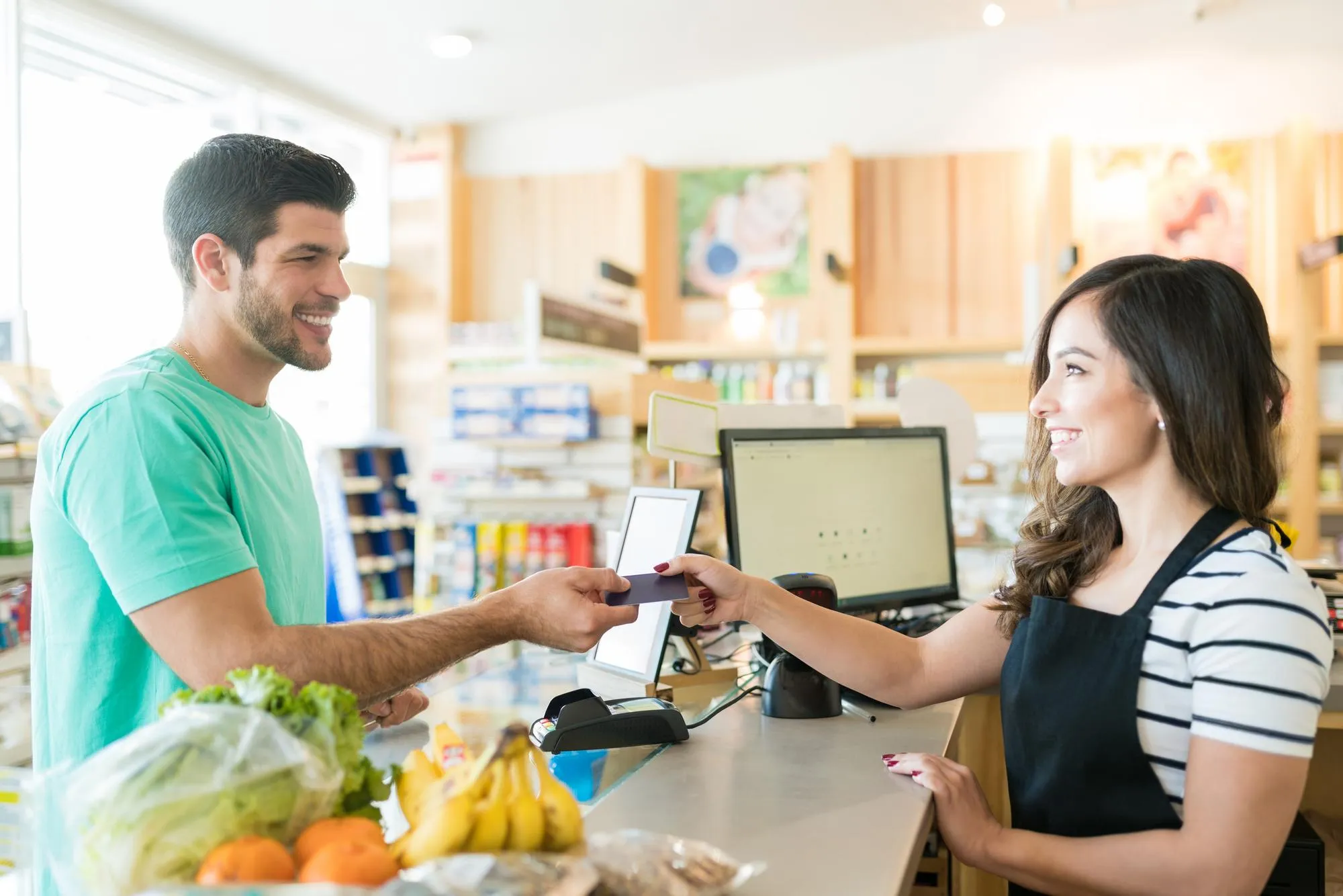 Pharmacist assisting a customer at checkout, showcasing how Pharmacy Clinical Services improve patient access to medications and enhance everyday healthcare support