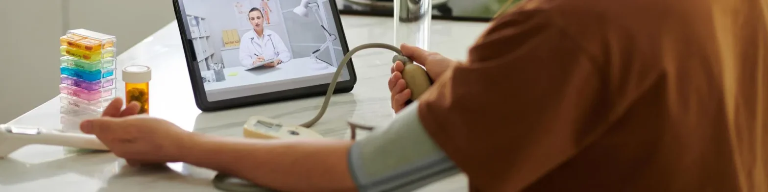 Patient measuring blood pressure during a virtual healthcare visit, showcasing how telehealth primary care and online prescription consultation enable remote monitoring and convenient care from home