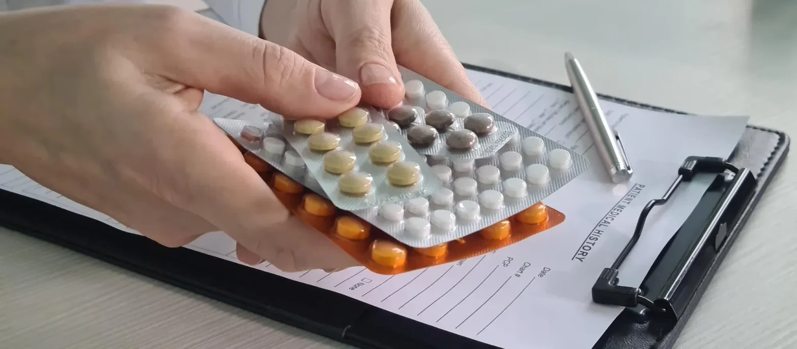 Blister packs of medications being handled over a prescription form, highlighting advanced Medication Packaging Services and secure tamper resistant packaging for safe and organized medication use