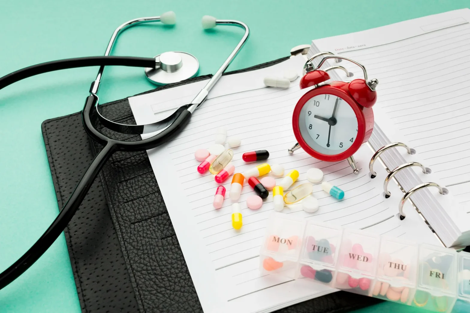 Medications, pill organizer, and alarm clock on a planner, highlighting the importance of staying on schedule with refills and relying on a nearby Pharmacy in Jacksonville for consistent care
