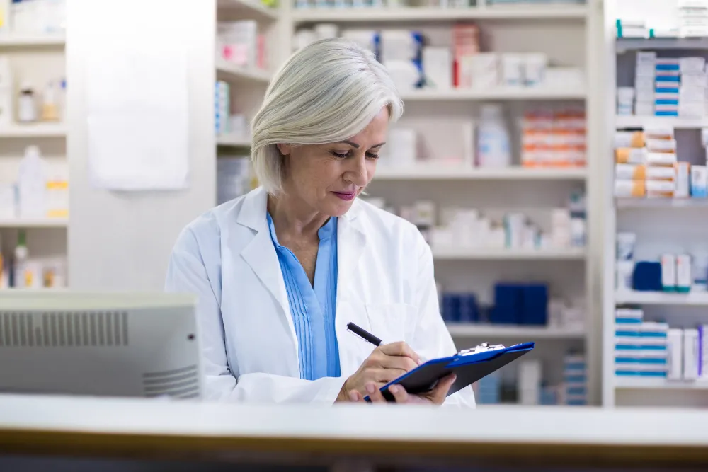 Clinical pharmacist updating patient medication records as part of pharmacy clinical care and prescription management services
