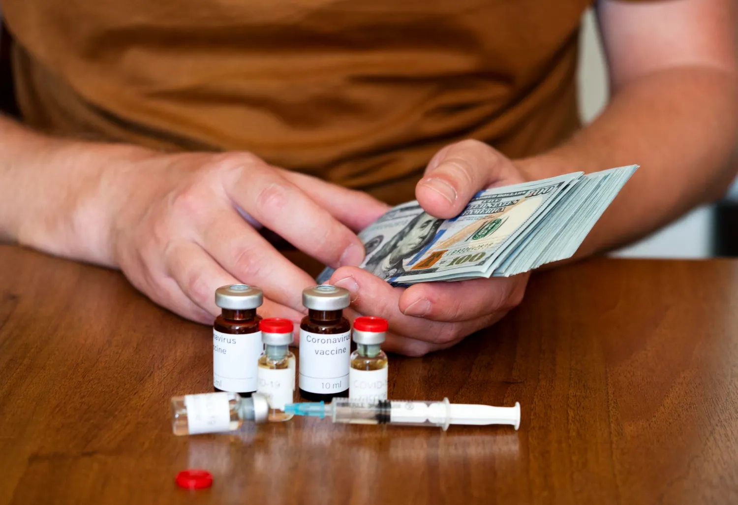 Patient holding cash beside specialty medication vials and syringes, highlighting the financial burden of specialty drugs and the support offered by a Specialty Pharmacy.