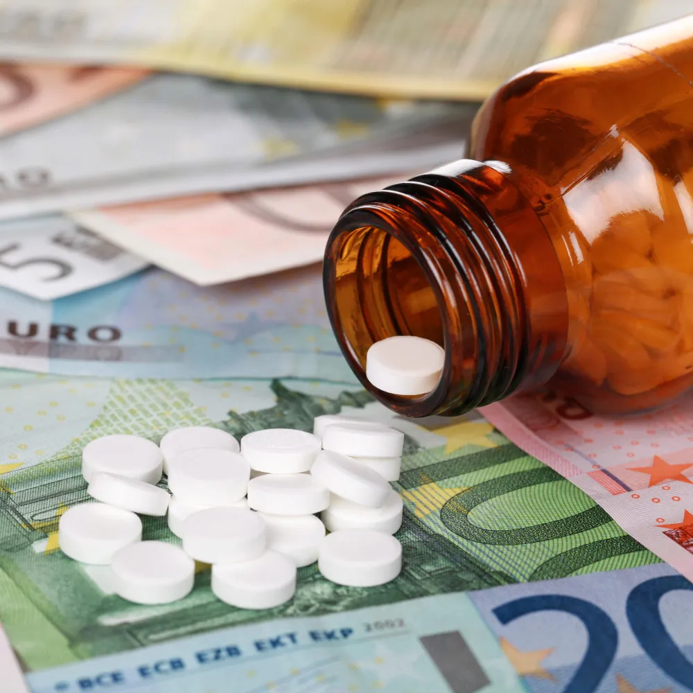 Prescription medication bottle and tablets placed on currency, representing the high cost of specialty medications and financial assistance available through a Specialty Pharmacy.