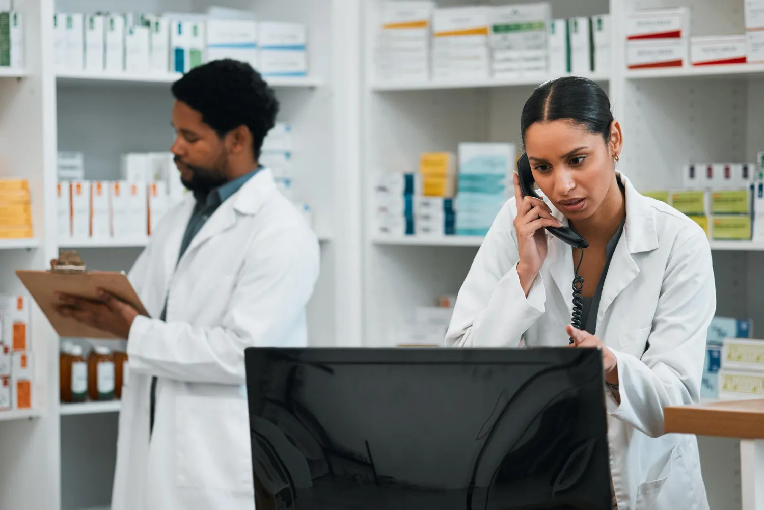 Pharmacists coordinating prescriptions and supporting pharmacy medication synchronization services with a patient to simplify refills and improve medication management.