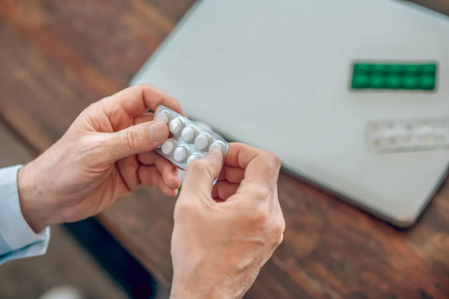 Patient holding a blister pack of medication while using a digital scale, representing medication synchronization Jacksonville services for organized prescription management.