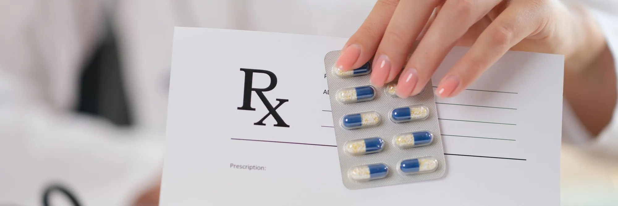 Patient holding a prescription and medication blister pack for medication synchronization.